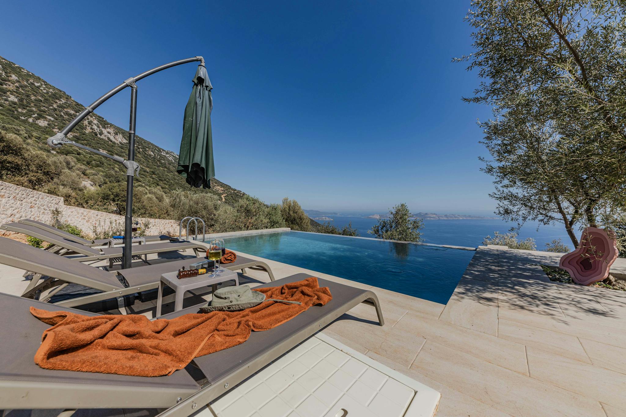Relaxing infinity pool with sea view and sun loungers, perfect for a summer getaway.
