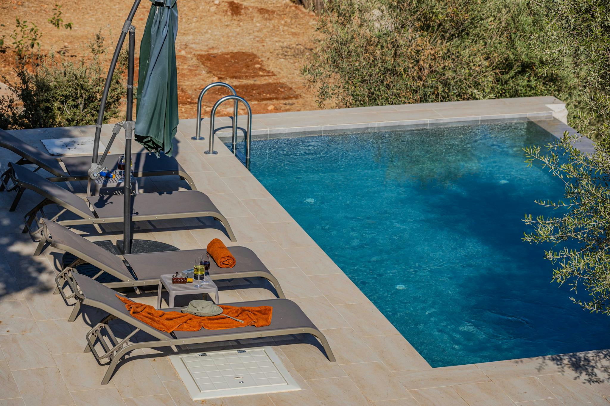 Serene poolside setting with loungers and umbrella at a tropical resort, ideal for relaxation and summer fun.